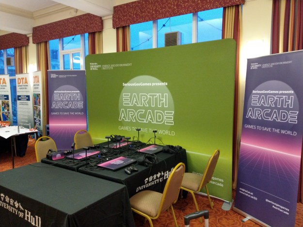 Laptops on a table as part of an event, surrounded by Earth Arcade banners.